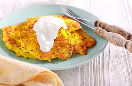 Courgette and cheese fritters with yogurt on plate