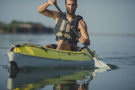 Young Caucasian man wearing life vest kayaking.