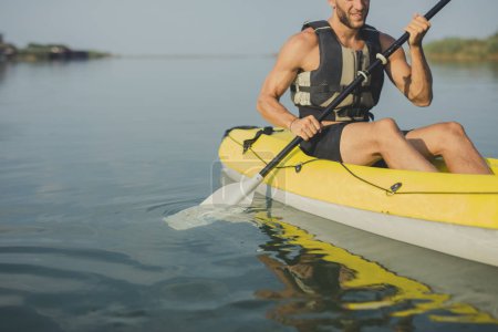 Young Caucasian man wearing life vest kayaking.