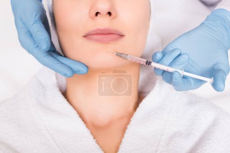 cropped view of beautician injecting face woman at beauty salon