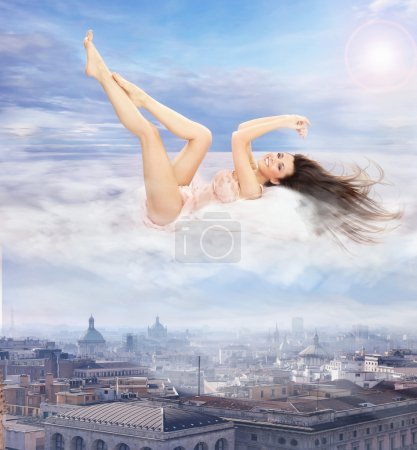 Conceptual photo of a beautiful brunette lying on clouds