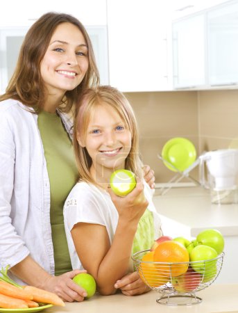 Happy Mother with Daughter eating Healthy food. Diet. Healthy Ea