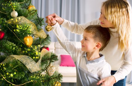 Kids decorating a Christmas tree with baubles in the living-room