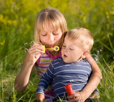 Happy Sister And Brother Blowing Soap Bubbles