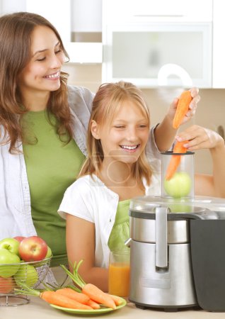 Happy Mother with Daughter eating Healthy food. Kitchen. Healthy