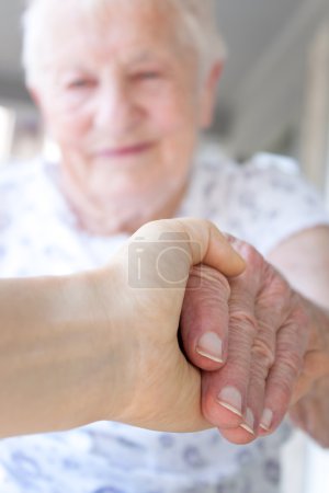 Young hand holding senior lady's hand