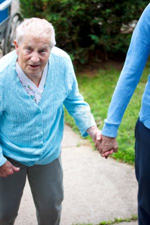 Senior lady walking with caregiver