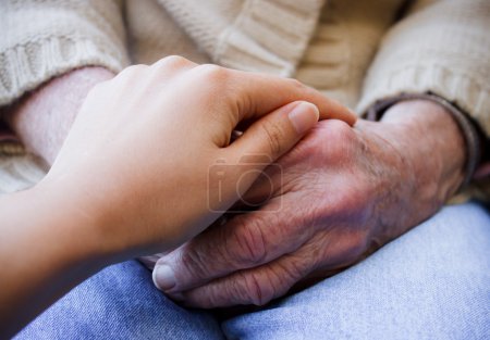 Young caregiver holding senior's hands
