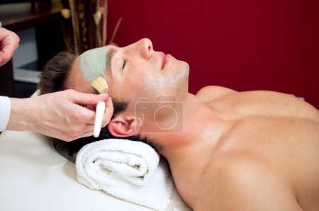 Applying a facial mask to a male customer