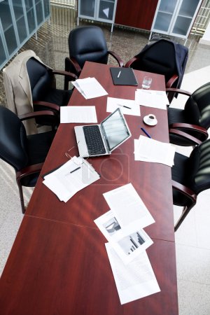 Empty boardroom: black chairs around table with business objects on it