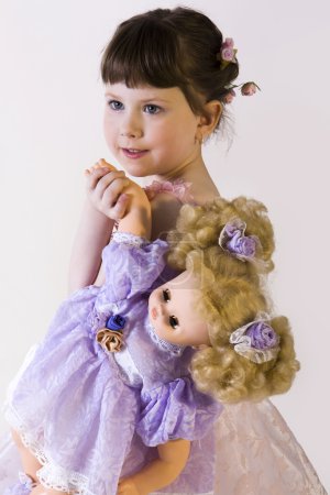 Sweet brunette little girl in pink dress holding her doll