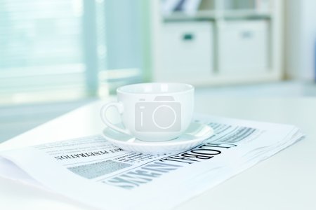 Cup and business newspaper