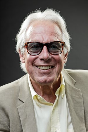 Smiling senior man in suit wearing sunglasses isolated on grey background.
