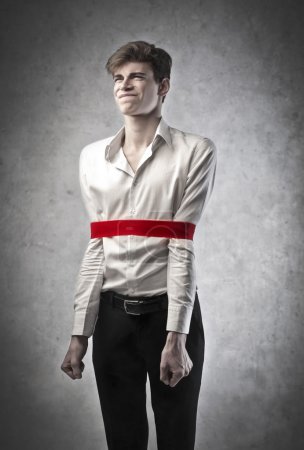 Frustrated young businessman with a red bandage blocking his movements