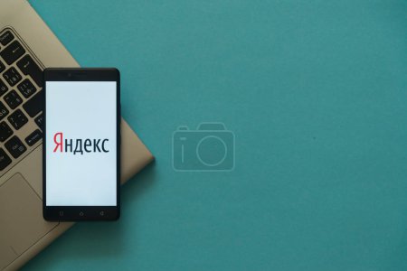 Yandex logo on smartphone placed on laptop keyboard.