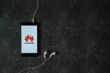 Huawei logo on smartphone screen on metal plate background.