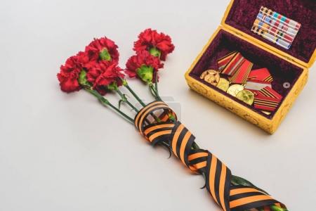 closeup shot of flowers wrapped by st. george ribbon and box with medals, victory day concept
