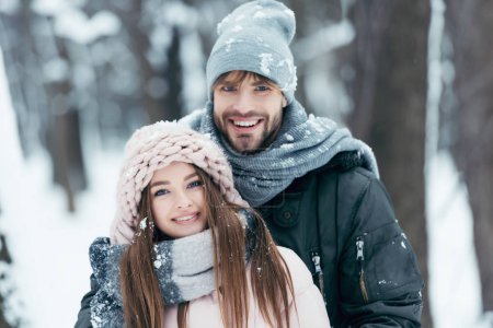 portrait of happy couple looking at camera in snowy park