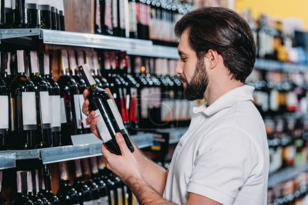 male shop assistant arranging alcohol in supermarket