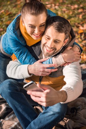Beautiful smiling couple looking at smartphone