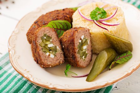 Zrazy cutlets with minced meat with pickled cucumber and eggs and garnish of bulgur