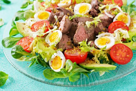 Warm salad from chicken liver, avocado, tomato and quail eggs. Healthy dinner. Dietary menu.