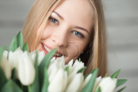 Close-up portrait of woman holding white tulips bouquet