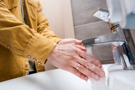 cropped view of woman washing hands at home