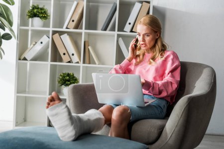 injured woman talking on smartphone while working from home 