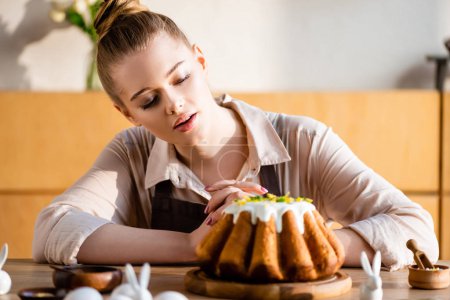 selective focus of attractive girl looking at tasty easter cake 