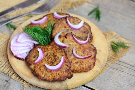 Homemade fried cutlets from chicken liver mince, carrot and onion. Quick easy liver cutlets on a wooden chopping board. Closeup