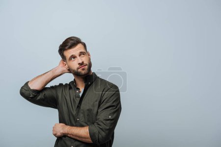Pensive man with hand near head looking up isolated on grey