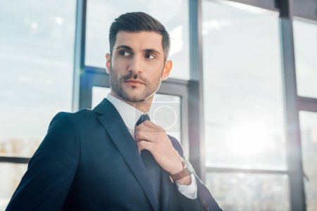 handsome professional businessman in suit standing in modern office