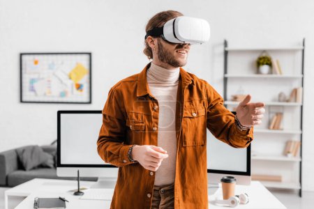 Smiling 3d artist gesturing while using virtual reality headset in office