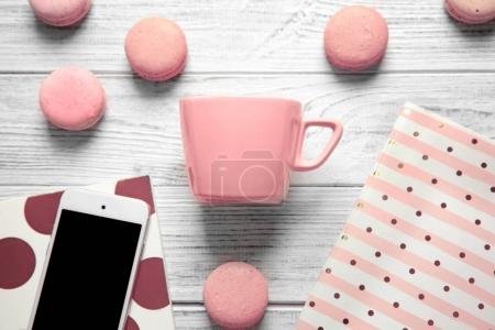 cup, macarons, phone and notebooks