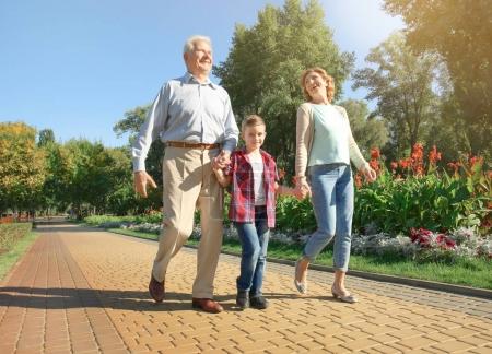 Elderly couple with grandson walking in park