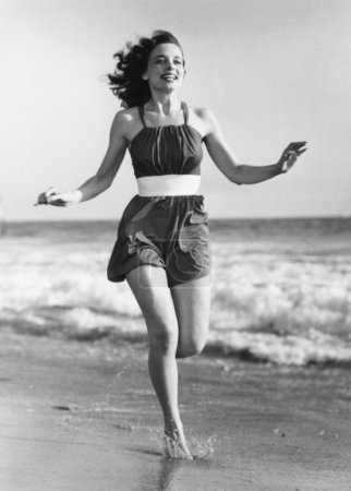 Cheerful young woman running on beach