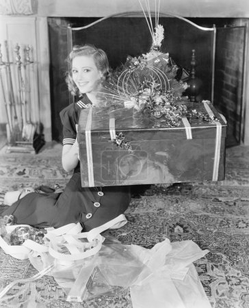 Young woman sitting in a living room showing a present