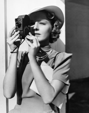 Portrait of a young woman taking a picture with a camera