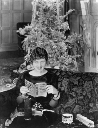 Young woman sitting on a couch with a Christmas tree in the background