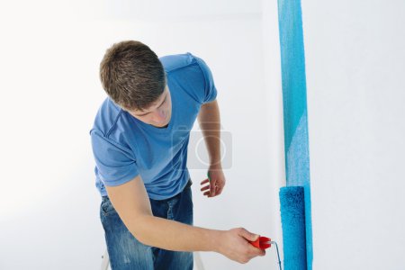 Handsome young man paint white wall in color