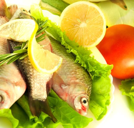 Fresh fish, crucian with a lemon and an onions, salad with olive oil