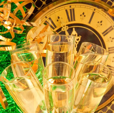 Christmas card. Glasses of champagne on New Year's Eve against an ancient wall clock