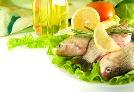 Fresh fish, crucian with a lemon and an onions, salad with olive oil