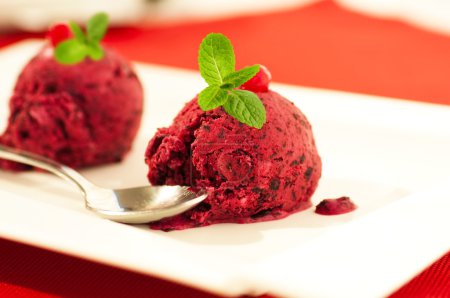 Ice-cream globule with a currant and mint on a red napkin
