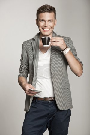 Smiling young man holding cup of tea