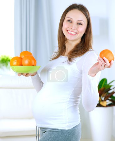 Pregnant Young Woman Eating Fruits at home
