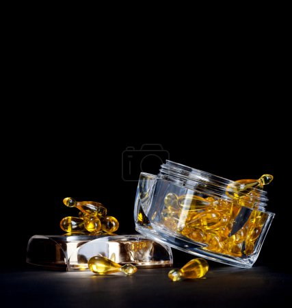 Aging cosmetics - capsules with treatment gel in glass can on black background