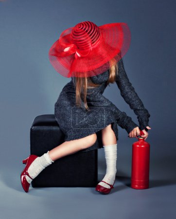 Fashion girl with fire extinguisher in big red hat and red shoes