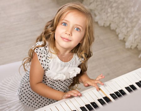 Little girl sitting near the piano